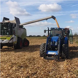 Une moissonneuse-batteuse décharge du maïs dans la benne d'un tracteur bleu à Ambillou près de Tours en Indre-et-Loire 37